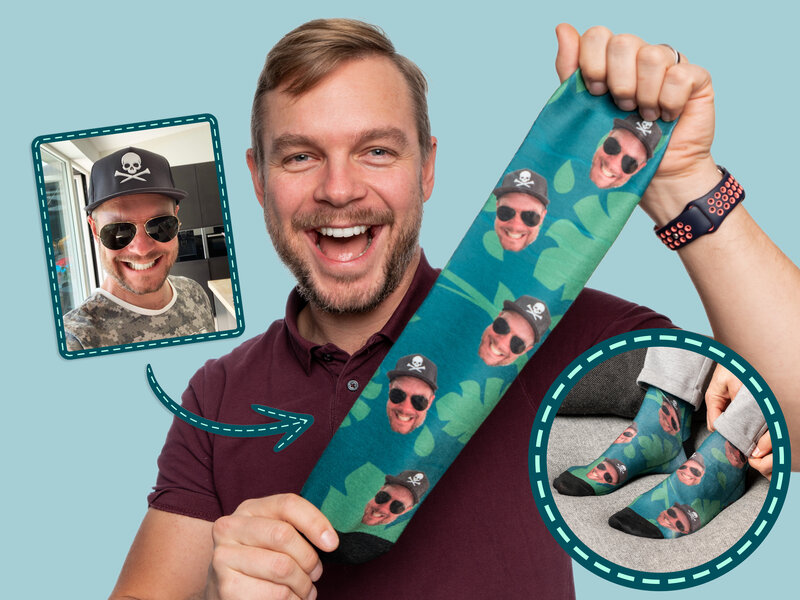 Ge ett par personliga strumpor i present eller julklapp! Personliga strumpor - bild på en kille som håller upp en grön strumpa försedd med egenuppladdat foto. Strumporna är även försedda med lite ljusare gröna bladmönster.