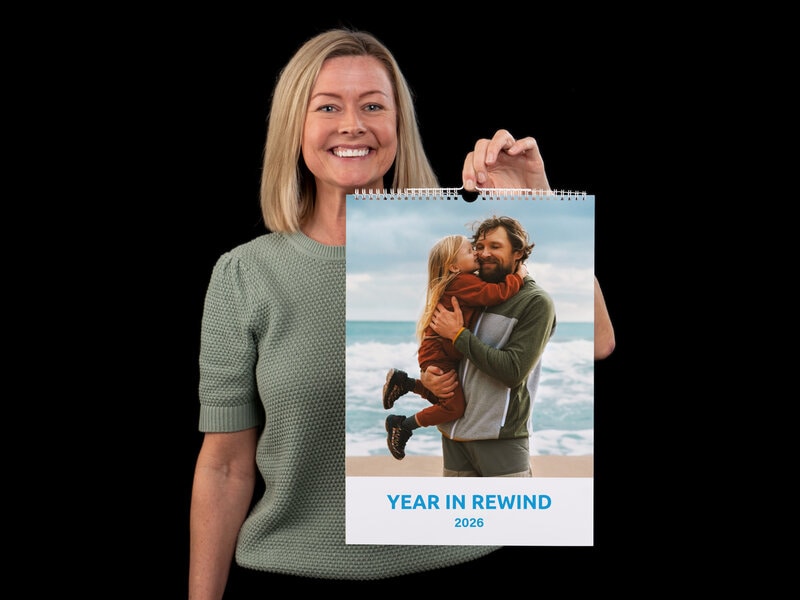 Ge en personlig fotokalender i julklapp till någon du gillar! Dam i grön tröja och halvlångt blont hår, hållandes en personlig fotokalender i ena handen.